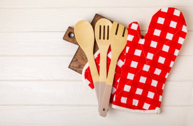 Mutfak eşyaları. Beyaz ahşap arka planda sıcak yemekler için fırın eldiveni ve tencere tutacağı. Yakın plan. Mesaj için yer. Boşluğu kopyala.