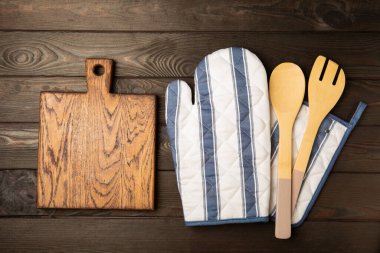 Mutfak eşyaları. Kahverengi ahşap arka planda sıcak yemekler için fırın eldiveni ve tencere tutacağı. Yakın plan. Mesaj için yer. Boşluğu kopyala.