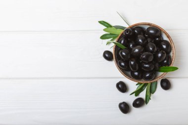 Beyaz ahşap arka planda siyah zeytin. Taze zeytin yapraklı zeytin yağı ve kâse içinde çeşitli zeytin türleri. Uzayı kopyala Mesaj için yer. Akdeniz yemekleri. Vejetaryen.