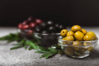 Mermer kaplamalı yeşil, siyah ve kırmızı zeytinler. Taze zeytin yapraklı zeytin yağı ve kâse içinde çeşitli zeytin türleri. Uzayı kopyala Mesaj için yer. Akdeniz yemekleri. Vejetaryen.