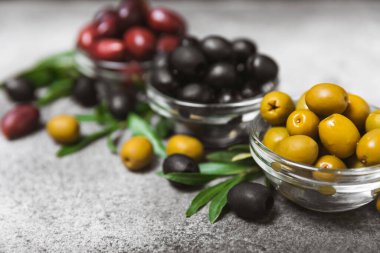 Mermer kaplamalı yeşil, siyah ve kırmızı zeytinler. Taze zeytin yapraklı zeytin yağı ve kâse içinde çeşitli zeytin türleri. Uzayı kopyala Mesaj için yer. Akdeniz yemekleri. Vejetaryen.