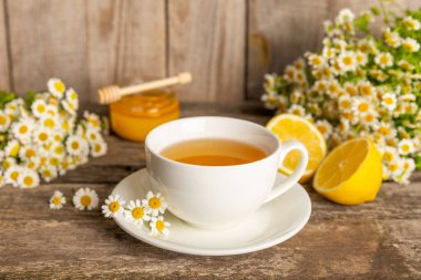 Kahverengi desenli beyaz bir fincanda papatya çayı. Papatya çiçekleriyle dolu doğal bir saat. Bitki çayı. Doğal şifacı konsepti. Sağlıklı detoks içeceği. Kapatın. Mesaj için yer. Boşluğu kopyala.