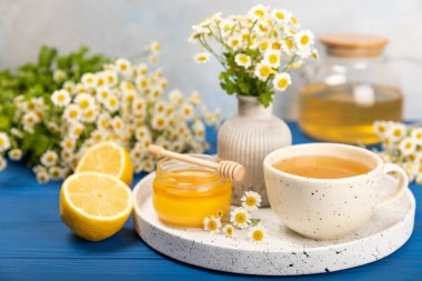 Mavi dokulu beyaz bir fincanda papatya çayı. Papatya çiçekleriyle dolu doğal bir saat. Bitki çayı. Dokunulmazlık çayı. Doğal iyileştirici kavramı. Sağlıklı detoks içeceği. Kapatın. Mesaj için yer. Boşluğu kopyala.