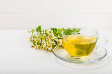 Papatya çayı, beyaz ahşap bir masada, bir buket papatya ile birlikte. Yakın plan. Uzayı kopyala Faydalı bitkisel içecekler, bağışıklık çayı. Doğal şifacı kavramı. Metin için yer..