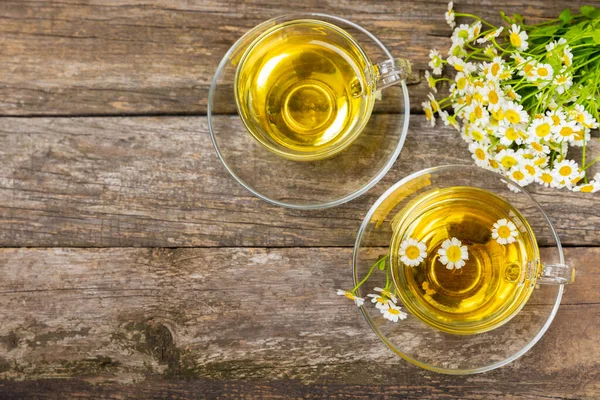 stock image Chamomile herbal tea in a glass cup on a brown wooden table with honey, lemon and chamomile bouquet. Close-up. Copy space. healthy herbal drinks, immunity tea. Natural healer concept.Place for text.