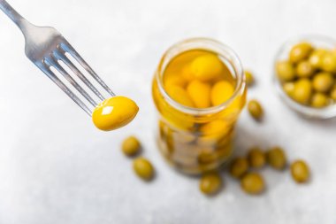 Hafif mermer bir arka planda cam kavanozda zeytin turşusu. Ahşap masada lezzetli zeytinler. Mesaj için yakın plan. Lezzetli sağlıklı Akdeniz yemekleri. Mutfakta sebze.