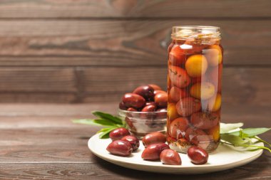 Cam kavanozda zeytin turşusu. Ahşap bir arka planda. Ahşap masada lezzetli zeytinler. Yakın plan. Lezzetli sağlıklı Akdeniz yemekleri. Vejetaryen.