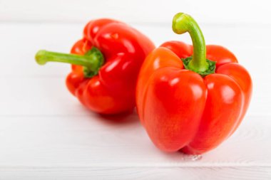 Beyaz desenli ahşap arka planda taze kırmızı dolma biber. Dolmalık biber. Sebzeler. Vejetaryen yemeği. Sağlıklı yiyecekler. Mesaj için yer. Kopyalanacak yer. Diyet kavramı.