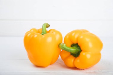 Beyaz desenli ahşap arka planda taze sarı dolma biber. Dolmalık biber. Sebzeler. Vejetaryen yemeği. Sağlıklı yiyecekler. Mesaj için yer. Kopyalanacak yer. Diyet kavramı.