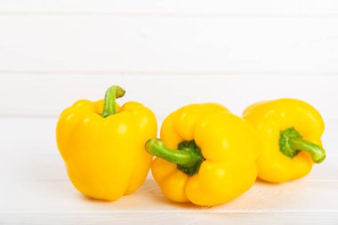 Beyaz desenli ahşap arka planda taze sarı dolma biber. Dolmalık biber. Sebzeler. Vejetaryen yemeği. Sağlıklı yiyecekler. Mesaj için yer. Kopyalanacak yer. Diyet kavramı.