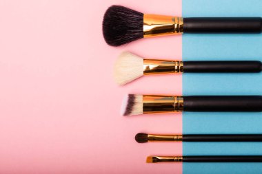 Pembe mavi arka planda makyaj fırçası. Makyaj için kozmetik ürün. Yaratıcı ve güzel moda konsepti. Moda. Kozmetik makyaj fırçası koleksiyonu, üst görüş, afiş. Mesaj için yer. MOCAP.