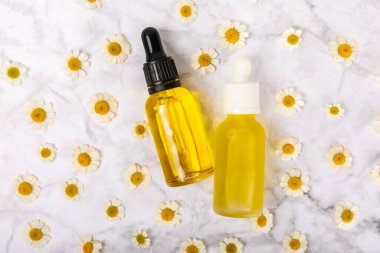Papatya yağı. İçinde papatya yağı bulunan cam şişe mermer kaplama. Papatya çiçekleri, yaklaşın. Aromaterapi, spa ve bitkisel ilaç malzemeleri. Kopya için yer var. Güzellik konsepti.