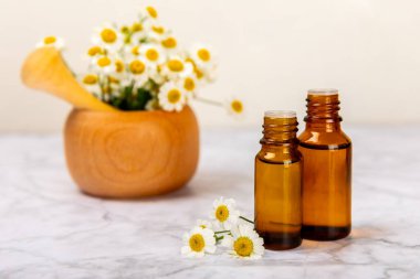 Papatya yağı. İçinde papatya yağı bulunan cam şişe mermer kaplama. Papatya çiçekleri, yaklaşın. Aromaterapi, spa ve bitkisel ilaç malzemeleri. Kopya için yer var. Güzellik konsepti.