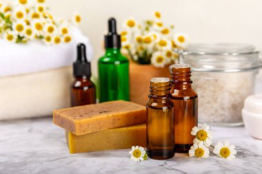 Papatya Spa 'sı. Temel yağ, deniz tuzu, papatya çiçeği, vücut kremi ve el yapımı sabun. Papatya çiçekli doğal bitkisel kozmetik. Dokulu bir arka plan. Güzellik konsepti. Kozmetik tüpü. 