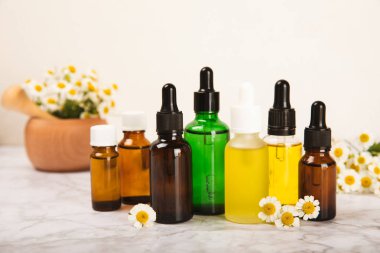 Papatya yağı. İçinde papatya yağı bulunan cam şişe mermer kaplama. Papatya çiçekleri, yaklaşın. Aromaterapi, spa ve bitkisel ilaç malzemeleri. Kopya için yer var. Güzellik konsepti.