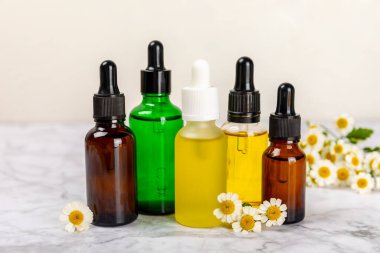 Papatya yağı. İçinde papatya yağı bulunan cam şişe mermer kaplama. Papatya çiçekleri, yaklaşın. Aromaterapi, spa ve bitkisel ilaç malzemeleri. Kopya için yer var. Güzellik konsepti.