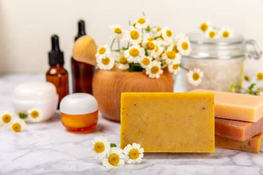 Papatya Spa 'sı. Temel yağ, deniz tuzu, papatya çiçeği, vücut kremi ve el yapımı sabun. Papatya çiçekli doğal bitkisel kozmetik. Dokulu bir arka plan. Güzellik konsepti. Kozmetik tüpü. 