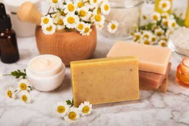 Papatya Spa 'sı. Temel yağ, deniz tuzu, papatya çiçeği, vücut kremi ve el yapımı sabun. Papatya çiçekli doğal bitkisel kozmetik. Dokulu bir arka plan. Güzellik konsepti. Kozmetik tüpü. 