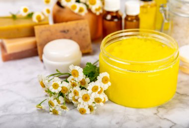 Papatya Spa 'sı. Temel yağ, deniz tuzu, papatya çiçeği, vücut kremi ve el yapımı sabun. Papatya çiçekli doğal bitkisel kozmetik. Dokulu bir arka plan. Güzellik konsepti. Kozmetik tüpü. 