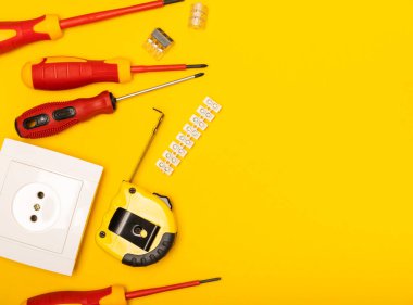 Sarı zemin üzerindeki elektrik teçhizatı kopya alanı ile üst görünüm. Elektrik aracı seti. Çoklu metre, testçi, tornavida, kesiciler, koli bandı, lamba, mezura, mezura ve kablo..