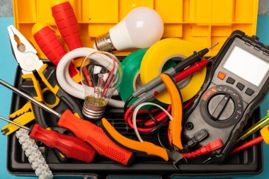 Mavi arka planda kopyalanmış elektrik teçhizatı. Üst görünüm. Elektrik aracı seti. Çoklu metre, test cihazı, tornavida, kesici, koli bandı, lamba, mezura, mezura ve kablo..