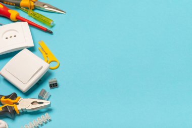 Mavi arka planda kopyalanmış elektrik teçhizatı. Üst görünüm. Elektrik aracı seti. Çoklu metre, test cihazı, tornavida, kesici, koli bandı, lamba, mezura, mezura ve kablo..
