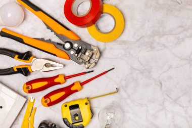 Mermer zemin üzerinde mermer arkaplan üzerinde elektrikli ekipman. Üst görünüm. Elektrik aracı seti. Çoklu metre, test cihazı, tornavida, kesiciler, koli bandı, lamba, mezura, mezura ve kablo..