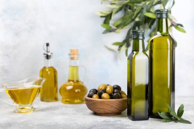 Beyaz dokuya sahip bir şişede zeytin yağı. Zeytin dallı ve meyveli yağ şişesi. Mesaj için yer. kopyalama alanı. Yemek yağı ve salata sosu.