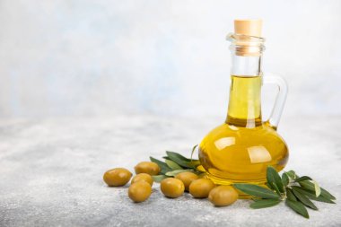 Beyaz dokuya sahip bir şişede zeytin yağı. Zeytin dallı ve meyveli yağ şişesi. Mesaj için yer. kopyalama alanı. Yemek yağı ve salata sosu.