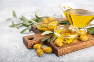 Cam bir kasede zeytinyağı ve dokulu bir arka planda sos kabı. Zeytin dallı ve meyveli yağ şişesi. Mesaj için yer. kopyalama alanı. Yemek yağı ve salata sosu..