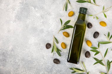 Beyaz dokuya sahip bir şişede zeytin yağı. Zeytin dallı ve meyveli yağ şişesi. Mesaj için yer. kopyalama alanı. Yemek yağı ve salata sosu.