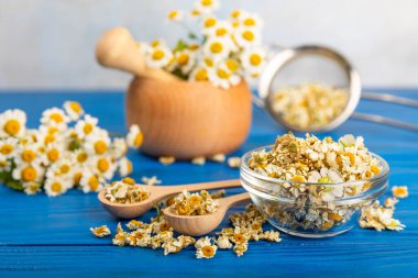 Papatya çayı, dokuma masasında bir kase içinde kurutulmuş papatya çayı. Papatya çayı. Papatya çayı. Düz yat. İçinde buket ve havan topu içinde papatya çiçeği olan bir kompozisyon. Bitkisel içecek. Rahatlatıcı ve tonik çay. 