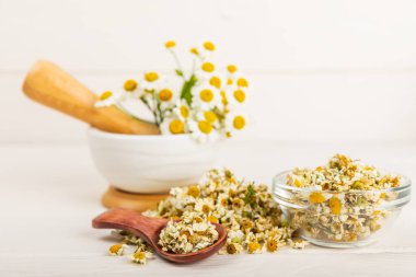 Papatya çayı, dokuma masasında bir kase içinde kurutulmuş papatya çayı. Papatya çayı. Papatya çayı. Düz yat. İçinde buket ve havan topu içinde papatya çiçeği olan bir kompozisyon. Bitkisel içecek. Rahatlatıcı ve tonik çay. 