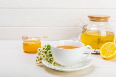 Çiçek tomurcuklu papatya çayı, beyaz ahşap bir masada bal ve limon ve bir buket papatya çayı. Yararlı bitkisel içecekler ve doğal iyileştirici konsept. Dokunulmazlık Çayı. Kapatın. Boşluğu kopyala.