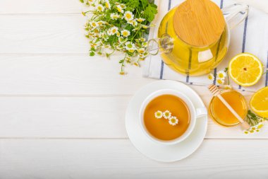 Çiçek tomurcuklu papatya çayı, beyaz ahşap bir masada bal ve limon ve bir buket papatya çayı. Yararlı bitkisel içecekler ve doğal iyileştirici konsept. Dokunulmazlık Çayı. Kapatın. Boşluğu kopyala.