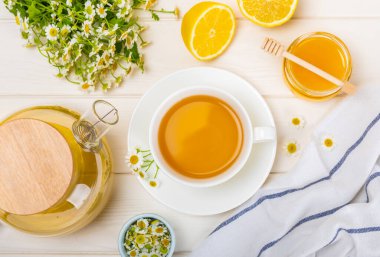 Çiçek tomurcuklu papatya çayı, beyaz ahşap bir masada bal ve limon ve bir buket papatya çayı. Yararlı bitkisel içecekler ve doğal iyileştirici konsept. Dokunulmazlık Çayı. Kapatın. Boşluğu kopyala.