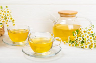 Çiçek tomurcuklu papatya çayı, beyaz ahşap bir masada bal ve limon ve bir buket papatya çayı. Yararlı bitkisel içecekler ve doğal iyileştirici konsept. Dokunulmazlık Çayı. Kapatın. Boşluğu kopyala.