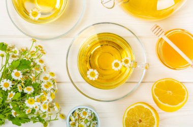 Çiçek tomurcuklu papatya çayı, beyaz ahşap bir masada bal ve limon ve bir buket papatya çayı. Yararlı bitkisel içecekler ve doğal iyileştirici konsept. Dokunulmazlık Çayı. Kapatın. Boşluğu kopyala.