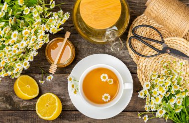 Çiçek tomurcuklu papatya çayı, kahverengi ahşap bir masada bal ve limon ve bir buket papatya çayı. Yararlı bitkisel içecekler ve doğal iyileştirici konsept. Dokunulmazlık Çayı. Kapatın. Boşluğu kopyala.