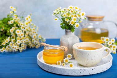 Mavi ahşap bir masada çiçek tomurcukları ve bir buket papatya çiçekli papatya çayı. Yararlı bitkisel içecekler ve doğal iyileştirici konsept. Dokunulmazlık Çayı. Kapatın. Boşluğu kopyala.