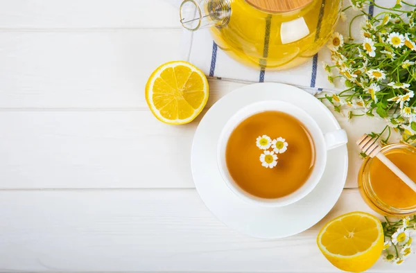 Çiçek tomurcuklu papatya çayı, beyaz ahşap bir masada bal ve limon ve bir buket papatya çayı. Yararlı bitkisel içecekler ve doğal iyileştirici konsept. Dokunulmazlık Çayı. Kapatın. Boşluğu kopyala.