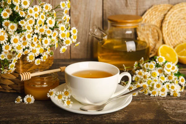 Çiçek tomurcuklu papatya çayı, kahverengi ahşap bir masada bal ve limon ve bir buket papatya çayı. Yararlı bitkisel içecekler ve doğal iyileştirici konsept. Dokunulmazlık Çayı. Kapatın. Boşluğu kopyala.