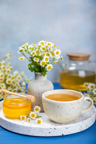 Mavi ahşap bir masada çiçek tomurcukları ve bir buket papatya çiçekli papatya çayı. Yararlı bitkisel içecekler ve doğal iyileştirici konsept. Dokunulmazlık Çayı. Kapatın. Boşluğu kopyala.