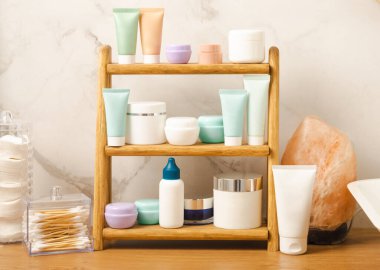 Banyodaki rafta makyaj malzemeleri var. Kozmetik tüpü. Temizleyici, yüz ve vücut kremi yüz silindiri ve gua sha, tonik. Tuvaletin içinde kozmetik ürünleri olan raflar. Güzellik konsepti.. 