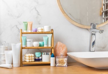Banyodaki rafta makyaj malzemeleri var. Kozmetik tüpü. Temizleyici, yüz ve vücut kremi yüz silindiri ve gua sha, tonik. Tuvaletin içinde kozmetik ürünleri olan raflar. Güzellik konsepti.. 
