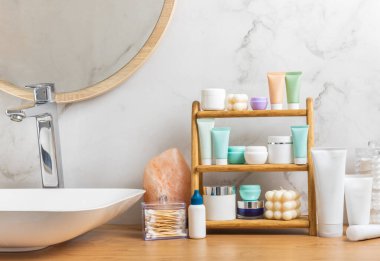 Banyodaki rafta makyaj malzemeleri var. Kozmetik tüpü. Temizleyici, yüz ve vücut kremi yüz silindiri ve gua sha, tonik. Tuvaletin içinde kozmetik ürünleri olan raflar. Güzellik konsepti.. 