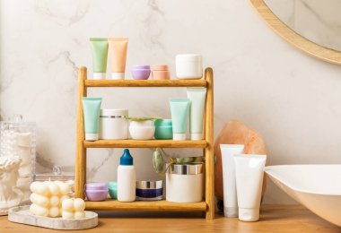 Banyodaki rafta makyaj malzemeleri var. Kozmetik tüpü. Temizleyici, yüz ve vücut kremi yüz silindiri ve gua sha, tonik. Tuvaletin içinde kozmetik ürünleri olan raflar. Güzellik konsepti.. 