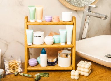 Banyodaki rafta makyaj malzemeleri var. Kozmetik tüpü. Temizleyici, yüz ve vücut kremi yüz silindiri ve gua sha, tonik. Tuvaletin içinde kozmetik ürünleri olan raflar. Güzellik konsepti.. 