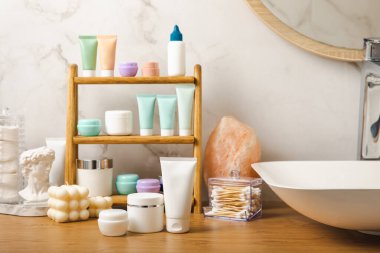 Banyodaki rafta makyaj malzemeleri var. Kozmetik tüpü. Temizleyici, yüz ve vücut kremi yüz silindiri ve gua sha, tonik. Tuvaletin içinde kozmetik ürünleri olan raflar. Güzellik konsepti.. 