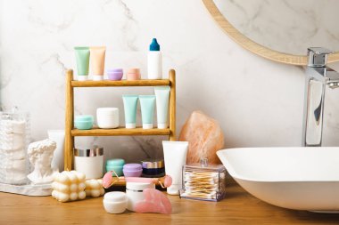 Banyodaki rafta makyaj malzemeleri var. Kozmetik tüpü. Temizleyici, yüz ve vücut kremi yüz silindiri ve gua sha, tonik. Tuvaletin içinde kozmetik ürünleri olan raflar. Güzellik konsepti.. 